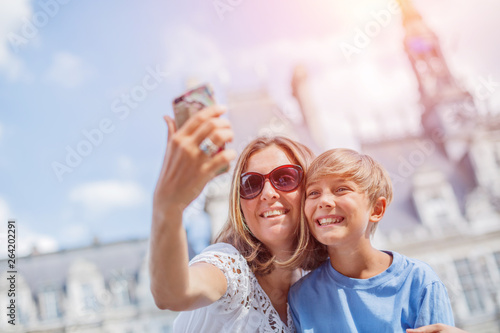Happy mother and her son making selfie near Hotel de Ville in Paris. Tourists enjoying their vacation in France.