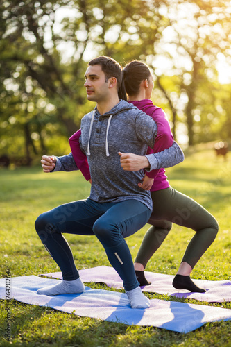 Couple is exercising in park. Exercise for sciatica recovery.