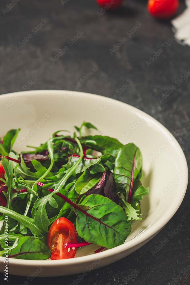 salad with tomato, lettuce, arugula, spinach and other leaves. food background. top salad with tomato, lettuce, arugula, spinach and other leaves. food background. top