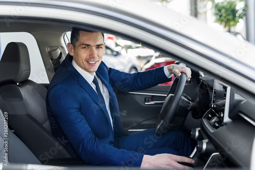 Young and happy businessman sitting in new car in showroom © RomanR