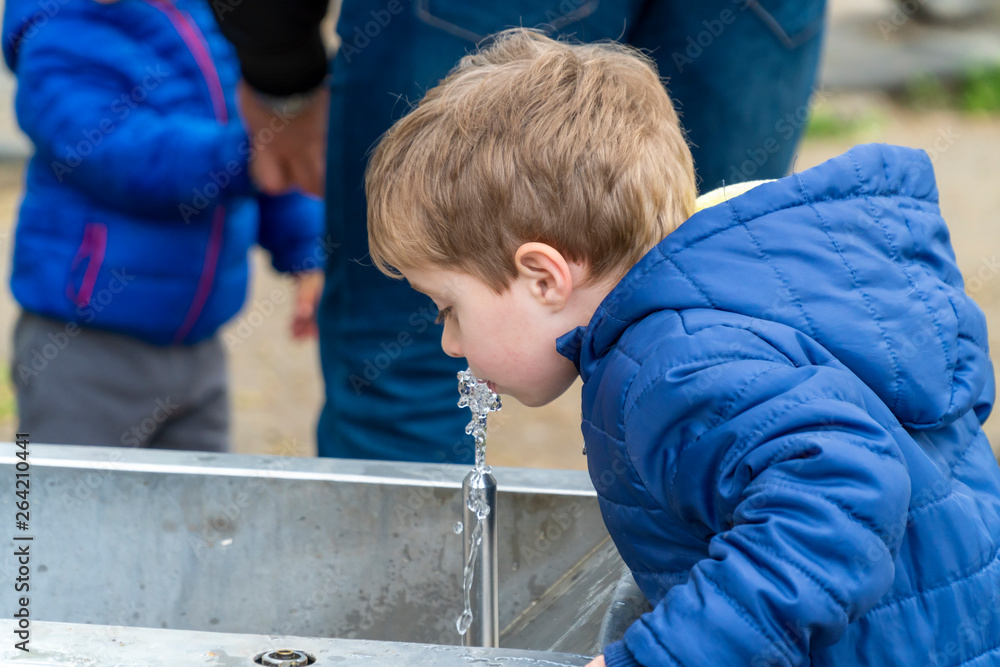 Small child drinking water in a park Small child drinking water in a park