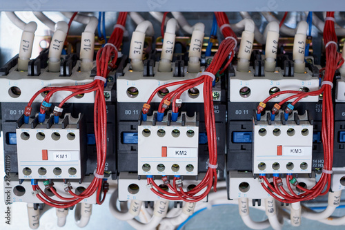 A number of electrical contactors with additional contacts installed in the electrical Cabinet. Cables and wires are connected to magnetic starters and contacts. Automation, control and management.