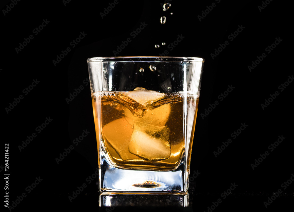 whiskey with ice in a steaming glass on a black background whiskey with ice in a steaming glass on a black background