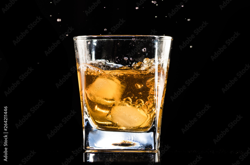 whiskey with ice in a steaming glass on a black background
