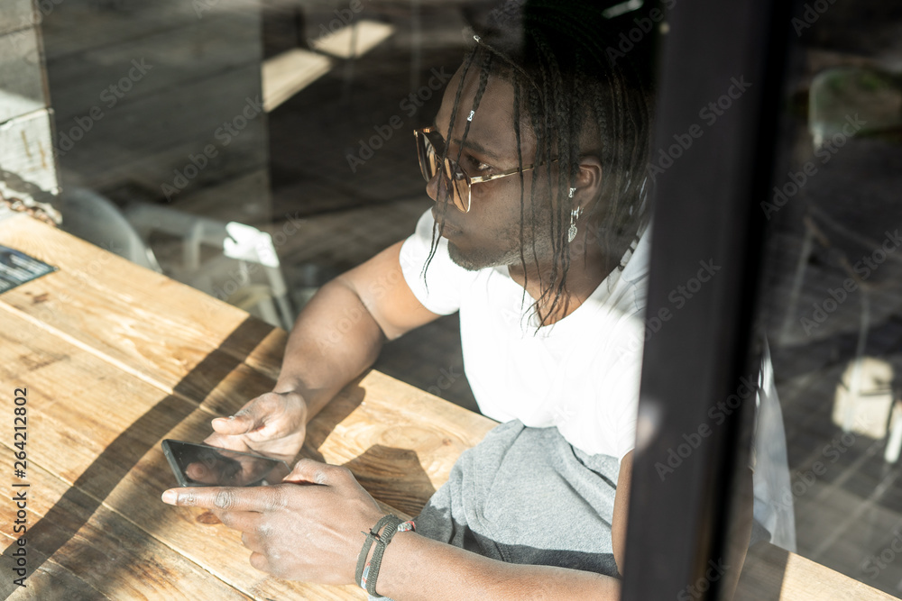 Handsome african american looking at a mobile phone in a coffee shop Handsome african american looking at a mobile phone in a coffee shop