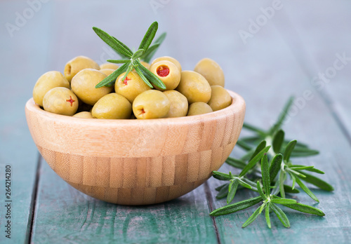 Green olives with rosemary on a wooden table