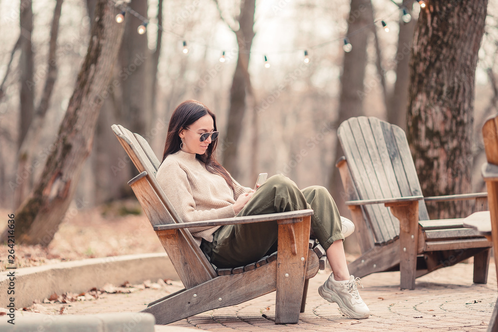 Caucasian woman with cellphone outdoors in cafe. Girl using mobile smartphone.