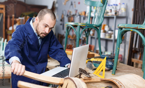 Carpenter using laptop in workshop