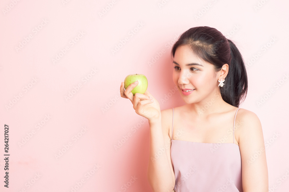 Healthy girl eating green apple on pink background Healthy girl eating green apple on pink background
