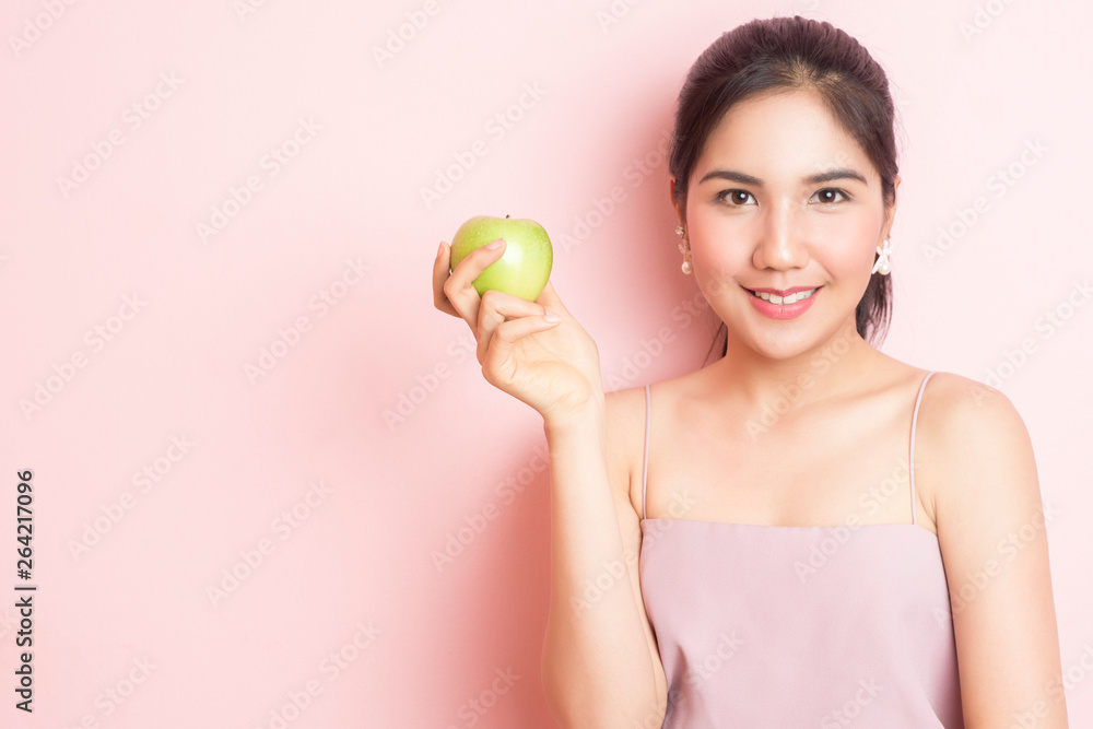 Healthy girl eating green apple on pink background Healthy girl eating green apple on pink background