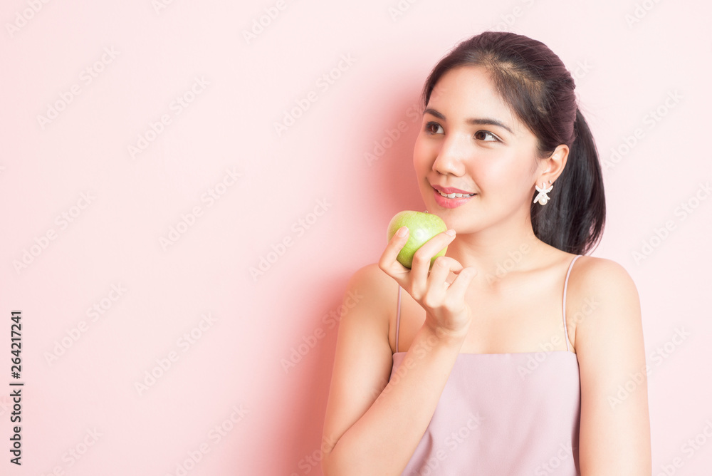 Healthy girl eating green apple on pink background Healthy girl eating green apple on pink background