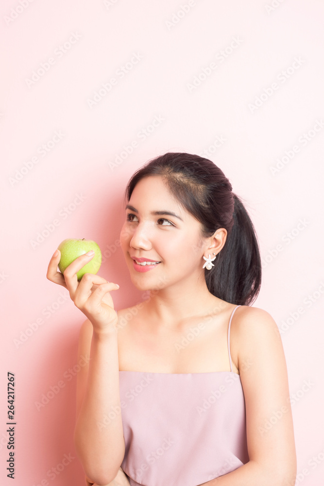 Healthy girl eating green apple on pink background Healthy girl eating green apple on pink background