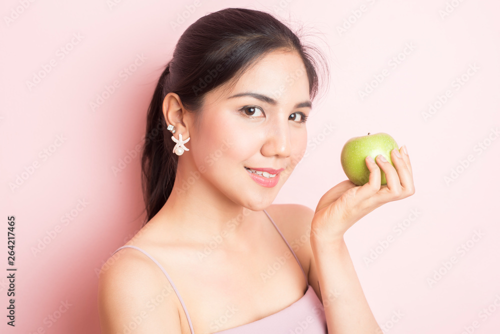 Healthy girl eating green apple on pink background Healthy girl eating green apple on pink background