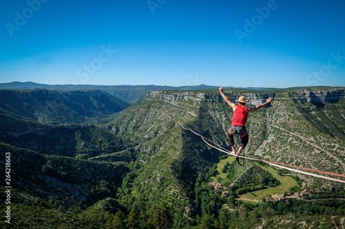 a man walking on the longest slackline ever in Navacelles circus (world humanity patrimony) at 300 meters high, Occitanie, Navacelles, France photo