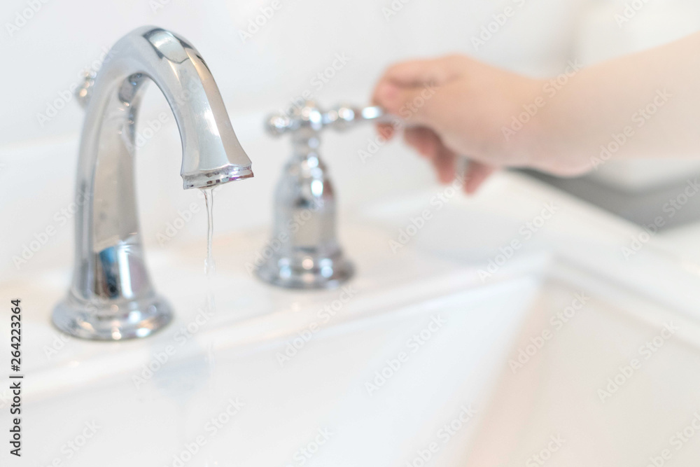 Save the water concept.Hand closing valve on sink in bathroom. Water dripping to stop running as hand turn off the faucet.Detect-a-Leak week. Save the water concept.Hand closing valve on sink in bathroom. Water dripping to stop running as hand turn off the faucet.Detect-a-Leak week.