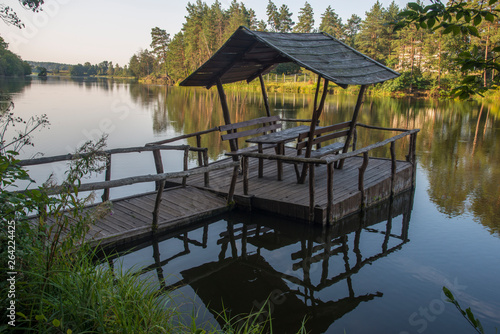 Wooden table with benches and canopy on a forest lake