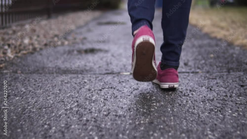 Red shoes on young teenager walking over debris on a wet sidewalk in slow motion. Red shoes on young teenager walking over debris on a wet sidewalk in slow motion.