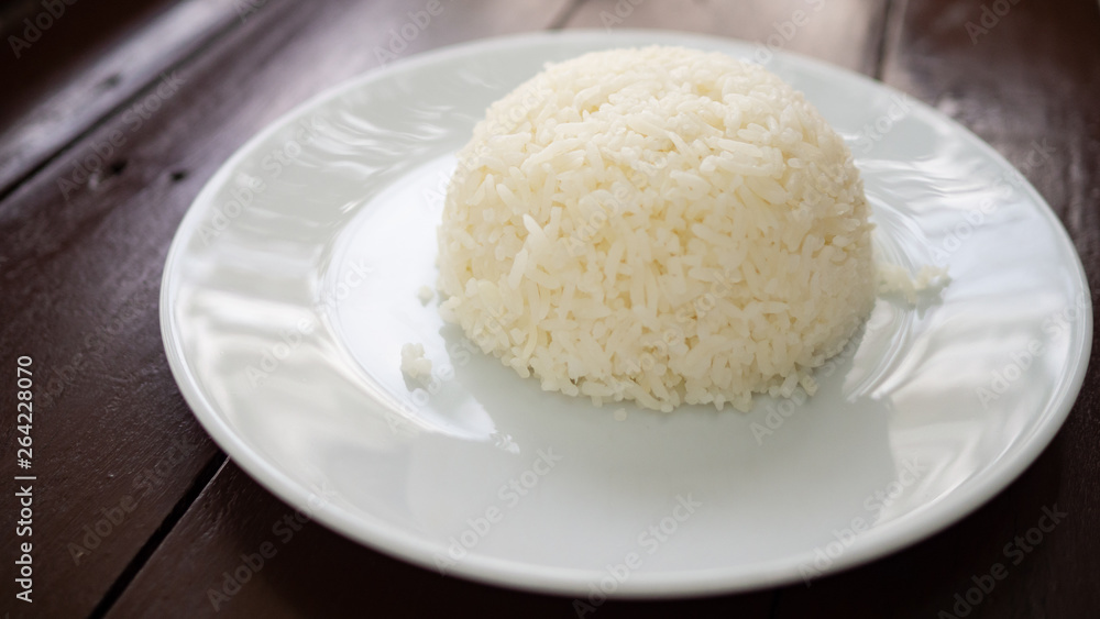 Rice in a white plate placed on a wooden table. Rice in a white plate placed on a wooden table.