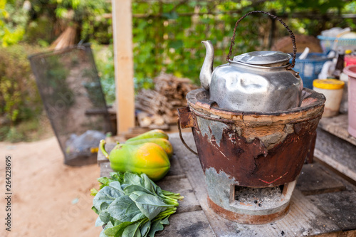 Old Thai kettle on thai charcoal stove with Green leafy vegetables and papaya put on a wooden table are Thai traditional kitchen style.