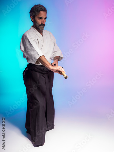 bearded man practicing aikido illuminated with colorful gels in studio photo with blue and pink background