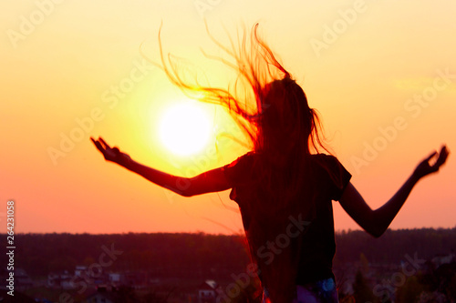 Silhouette Of Young Woman Holding Hands Up And Looking To The Sunset. People, Travel, Hobby, Happiness Concept.