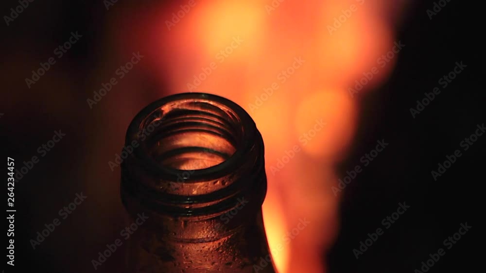 Boca de botella de refresco con fondo de fuego borroso Boca de botella de refresco con fondo de fuego borroso