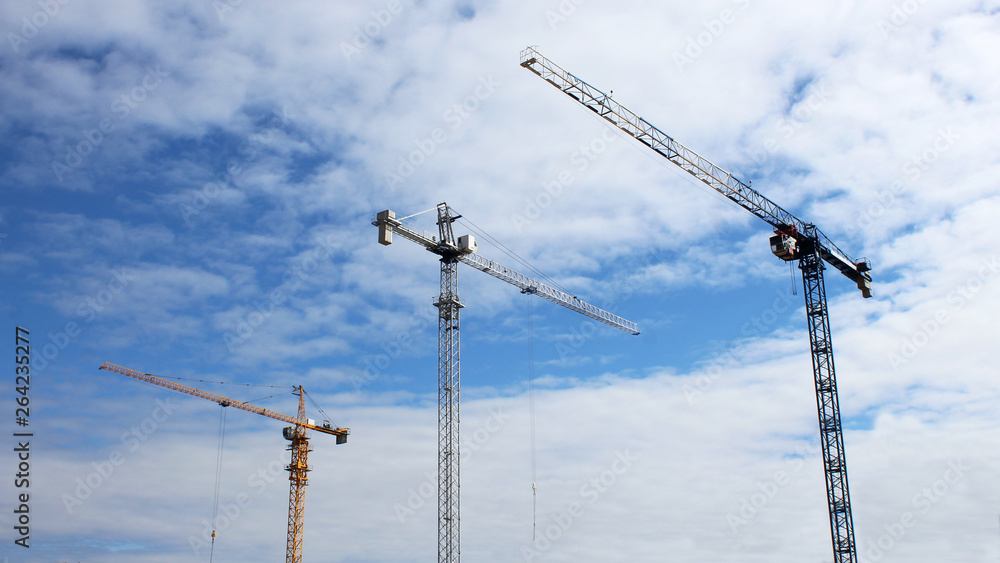 Construction site tower cranes against blue sky Construction site tower cranes against blue sky