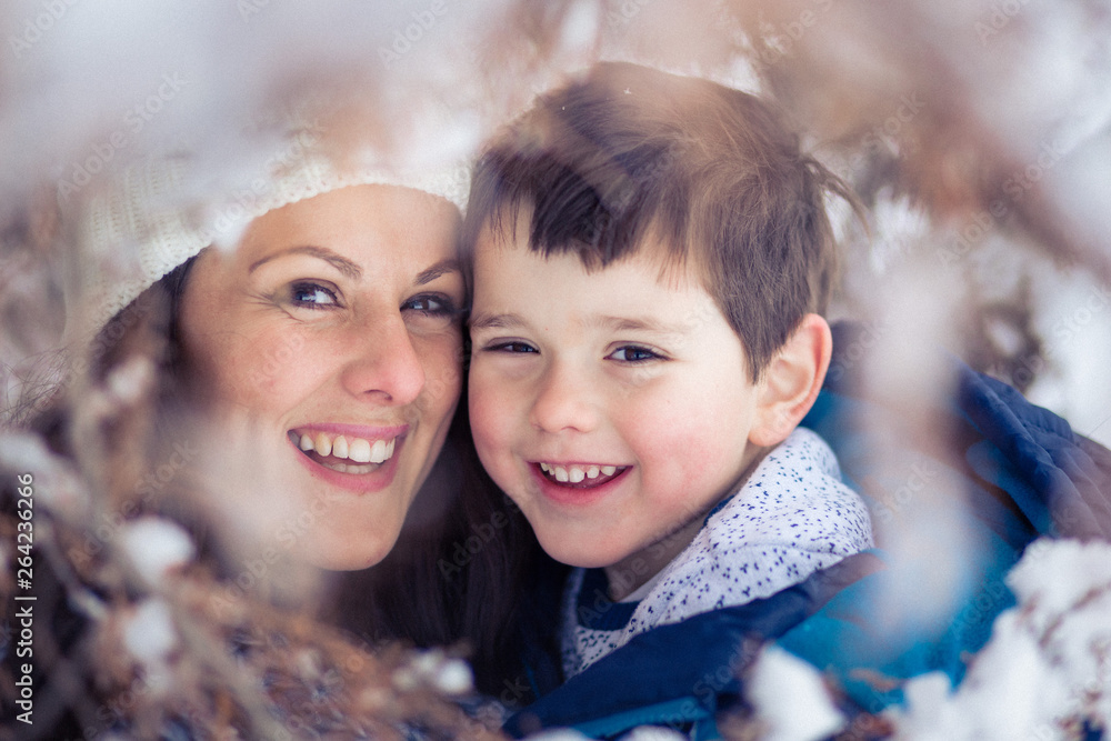 Obraz premium Young mom and her beautiful son hugging. Winter surrounding.