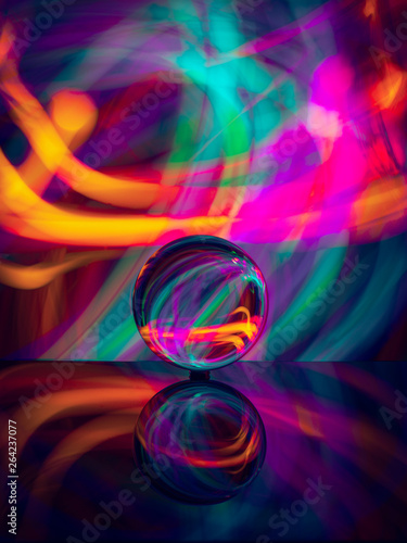 crystal ball on reflective surface with colorful lights background