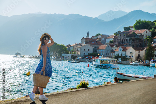 young pretty stylish woman walking by city quay. sea and mountains on background photo