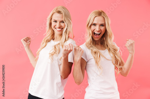 Cheerful blonde twins wearing in t-shirts rejoices