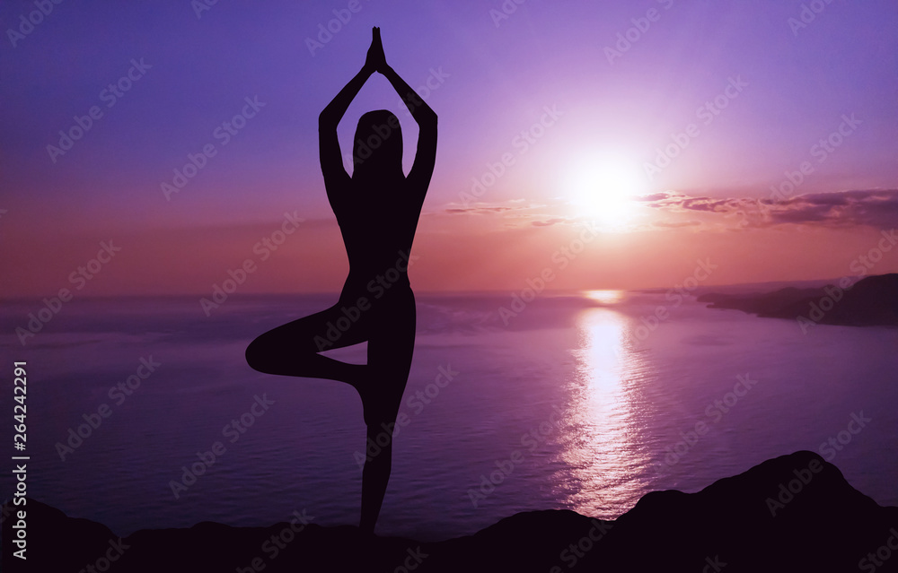 Woman practicing yoga at sunset.