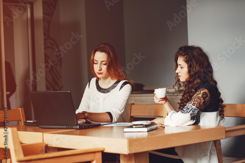 Girls are sitting at the table.Beautiful girls work in the office. Women with a computer