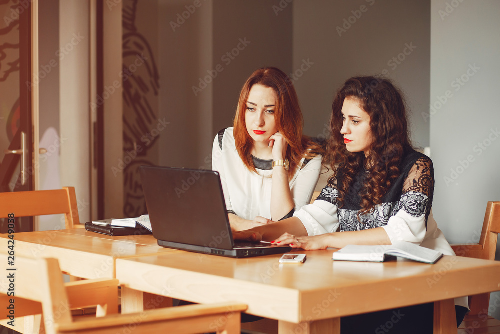 Girls are sitting at the table.Beautiful girls work in the office. Women with a computer Girls are sitting at the table.Beautiful girls work in the office. Women with a computer