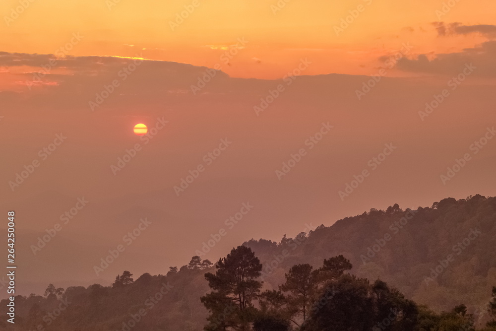view of sunset in cloudy sky above the hill with yellow sun light in the sky background, sunset at Huai Nam Dang National Park, Chiang Mai, Thailand.