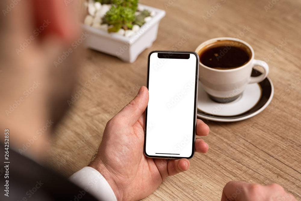 Business man holding phone with white empty screen at work place Business man holding phone with white empty screen at work place