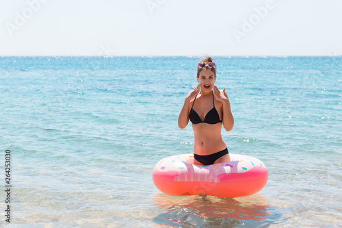 Woman relaxing with inflatable ring on the beach. shocked or surprise girl in the cold sea. Summer holidays and vacation concept