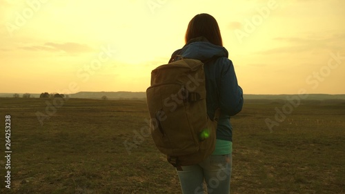 girl traveling with a backpack against the sky and the flare of sun. tourist young woman goes on a sunset to the mountains. desire for knowledge of the world. sports tourism concept. © zoteva87