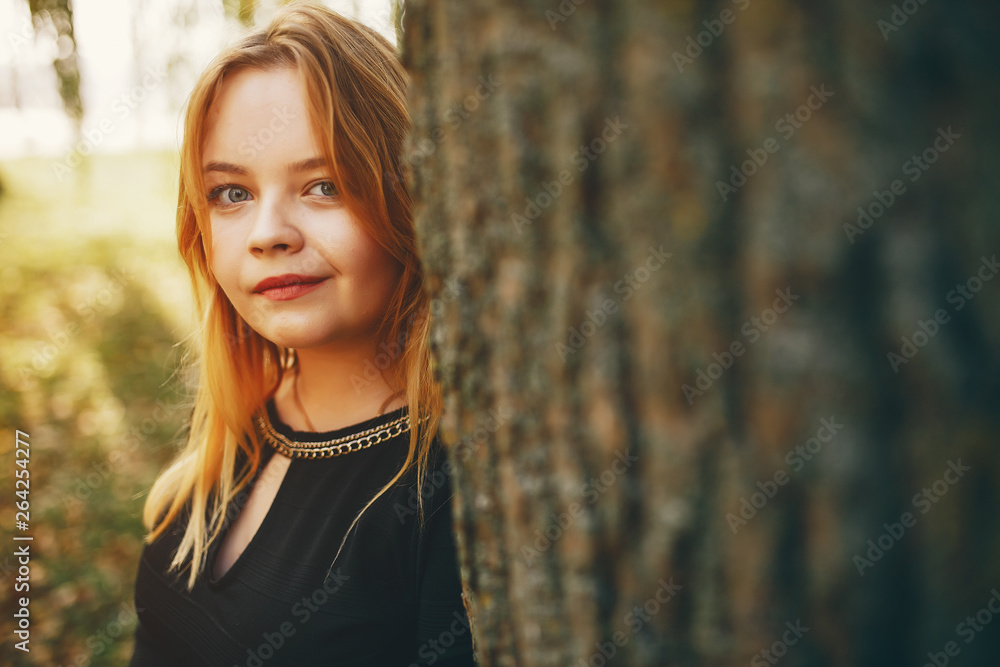 pretty cute girl with make up, dressed in black dress standing in a autumn park near tree pretty cute girl with make up, dressed in black dress standing in a autumn park near tree