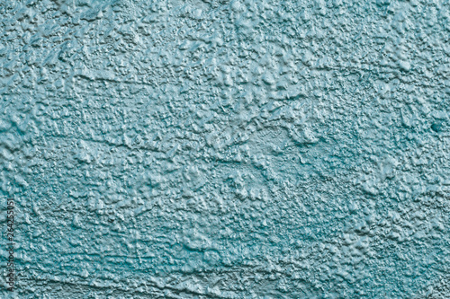 Texture of turquoise reflective rough concrete wall. Shiny blue wall background close-up. Painted rough blue cement wall. The shiny plaster. Reflective light turquoise surface. Reflecting uneven textu