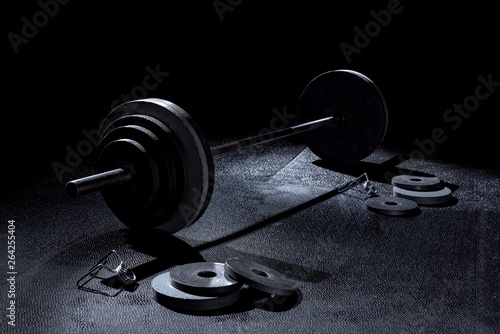 365 pound weight on barbell with weights on floor and collars in dramatic lighting in gym