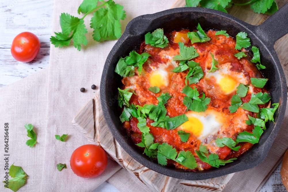 Shakshuka with tomato sauce and quail eggs topped with cilantro in a cast iron pan. Jewish cuisine meal Shakshuka with tomato sauce and quail eggs topped with cilantro in a cast iron pan. Jewish cuisine meal
