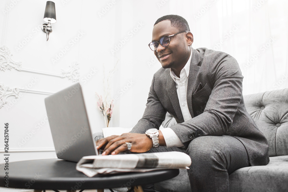Young African American businessman in a gray suit working behind a laptop. Young African American businessman in a gray suit working behind a laptop.