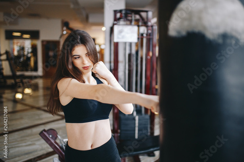 Beautiful girl in the gym. A woman performs exercises. The girl is boxing