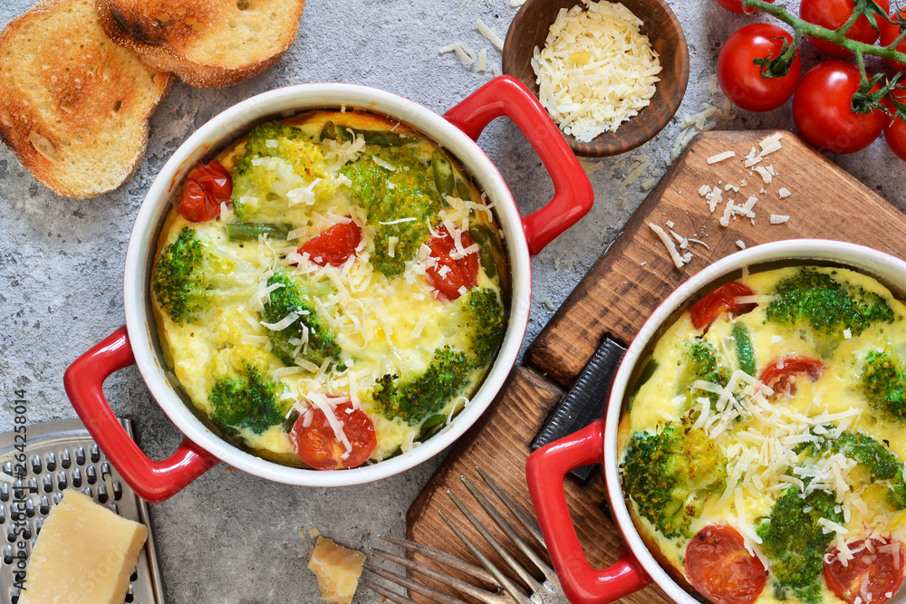 Casserole with broccoli, tomatoes and parmesan on a concrete background. View from above. Casserole with broccoli, tomatoes and parmesan on a concrete background. View from above.