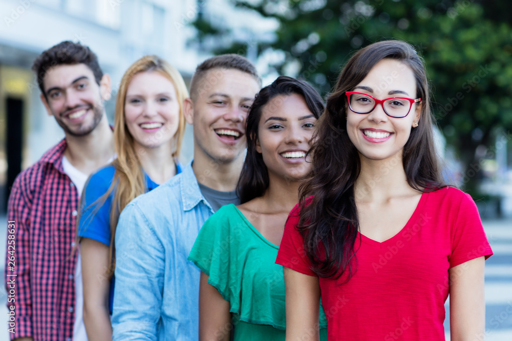 Junge Studentin mit Brille und Freunden in einer Reihe Junge Studentin mit Brille und Freunden in einer Reihe