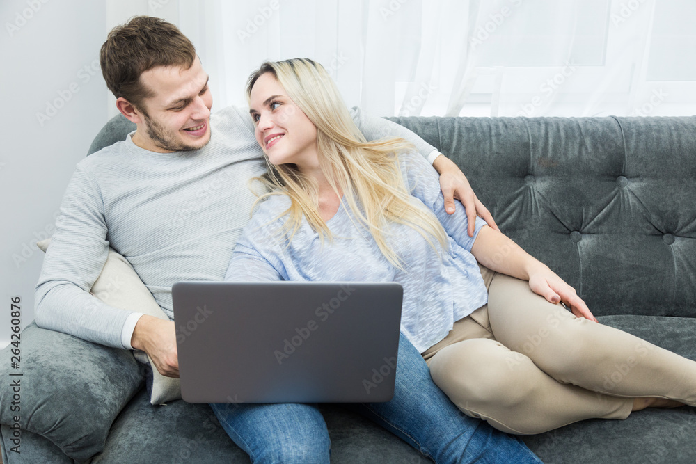 Young beautiful couple resting on the couch and watching online video from a laptop in the living room. Young beautiful couple resting on the couch and watching online video from a laptop in the living room.