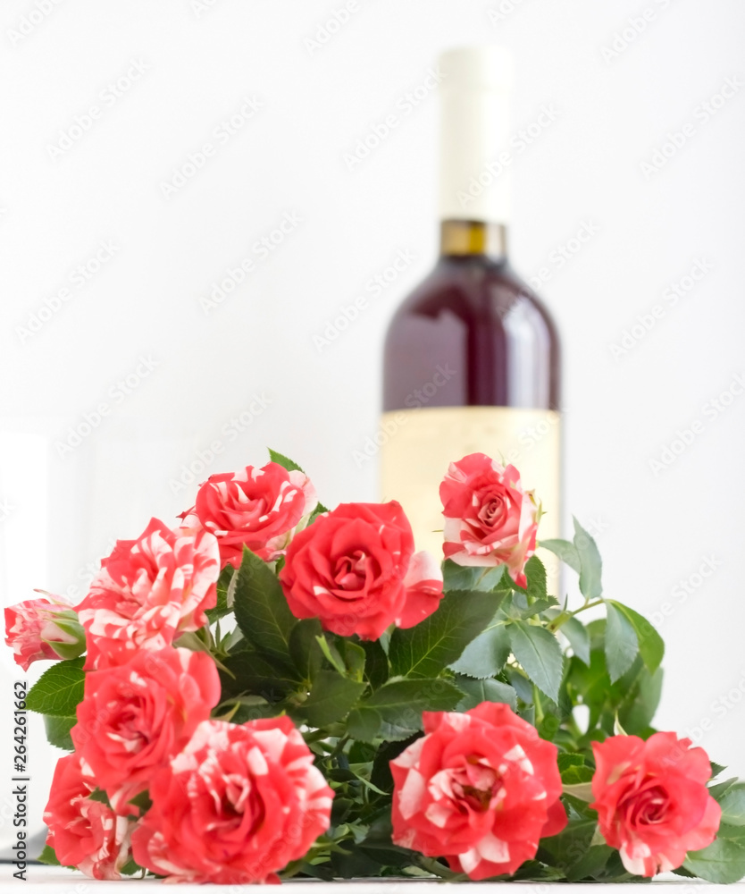 a bouquet of roses and a bottle of wine for a romantic evening. a bouquet of roses and a bottle of wine for a romantic evening.