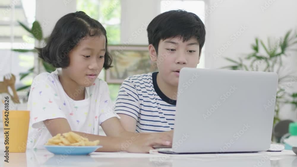 Young asian boy and girl playing with laptop computer at home. Children are playing online game on a laptop computer together. Dolly shoot 60fps. Young asian boy and girl playing with laptop computer at home. Children are playing online game on a laptop computer together. Dolly shoot 60fps.