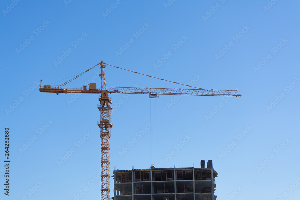 Building construction site with tower crane against blue sky